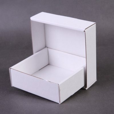 Kwadratowe pudełko tekturowe w białym kolorze o rozmiarze 10x10x3,5 cm.